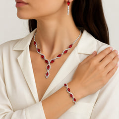 Red Crystal Jewellery Set – Sparkling Anniversary Birthday Christmas Gift for Her A close-up of a woman wearing a matching jewellery set featuring a silver-toned necklace and bracelet with deep red marquise-cut stones, alongside matching drop earrings. She is wearing a cream-colored blazer against a clean, light background.